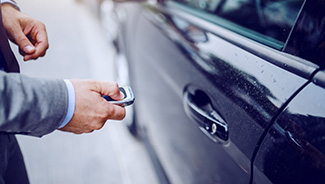 Close up of a person locking their vehicle with a key fob