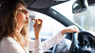 Woman applying lipstick while driving