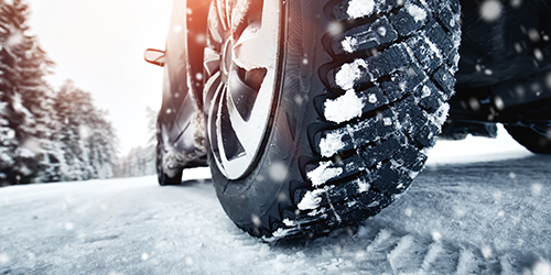 Snow tires on a vehicle driving on a snowy road.