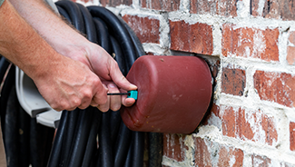 Hand installs outdoor faucet cover to protect plumbing from freezing in the winter