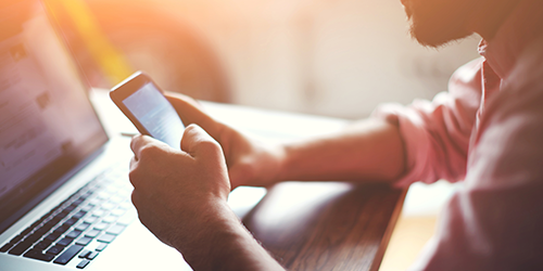 A person accessing their online account using their laptop and their phone.