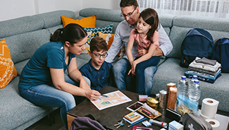 Two parents and two children review an evacuation plan near wildfire emergency supplies