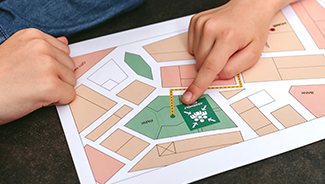 Close up of two hands pointing to a home’s location on a wildfire evacuation map